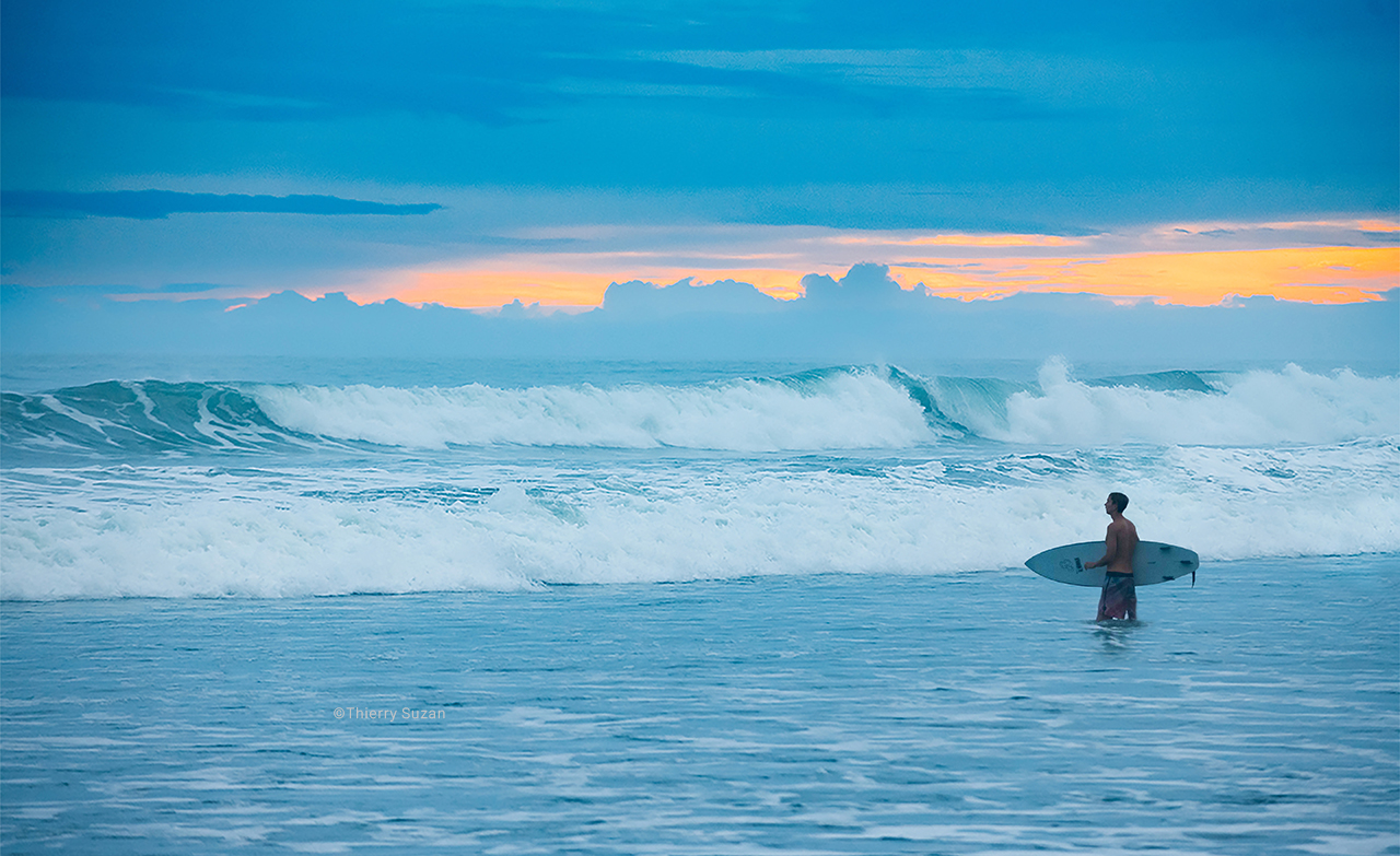 Surfer riding waves at Playa Ostional, Costa Rica