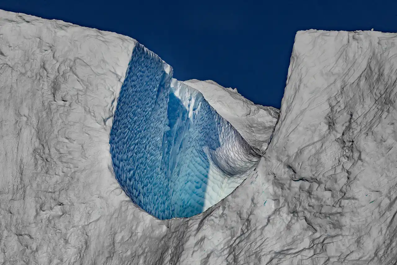 Natural arch carved into an ice cliff in Greenland