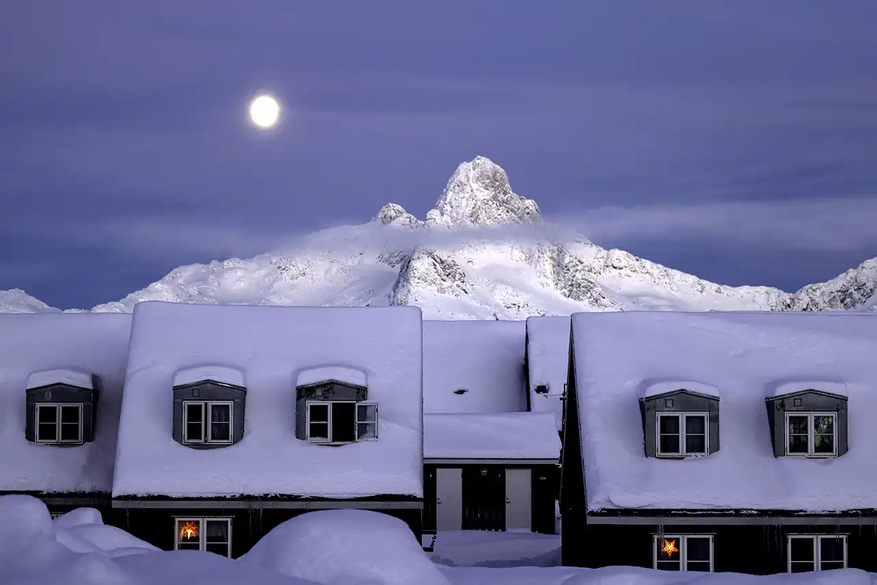 Lit houses at night in Greenland - moonlight and mountains