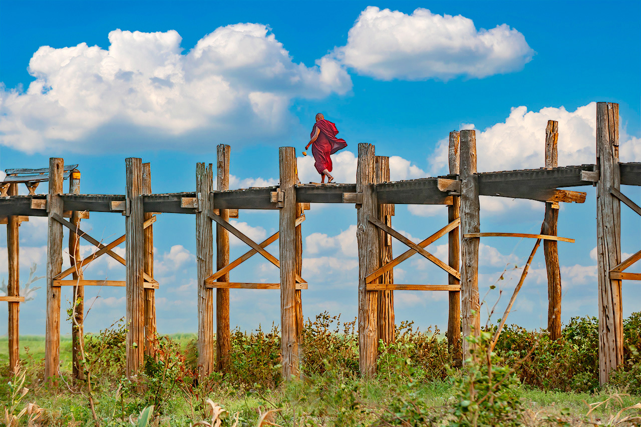 Buddhist monk walking on U Bein Bridge in Amarapura, Myanmar, at sunset