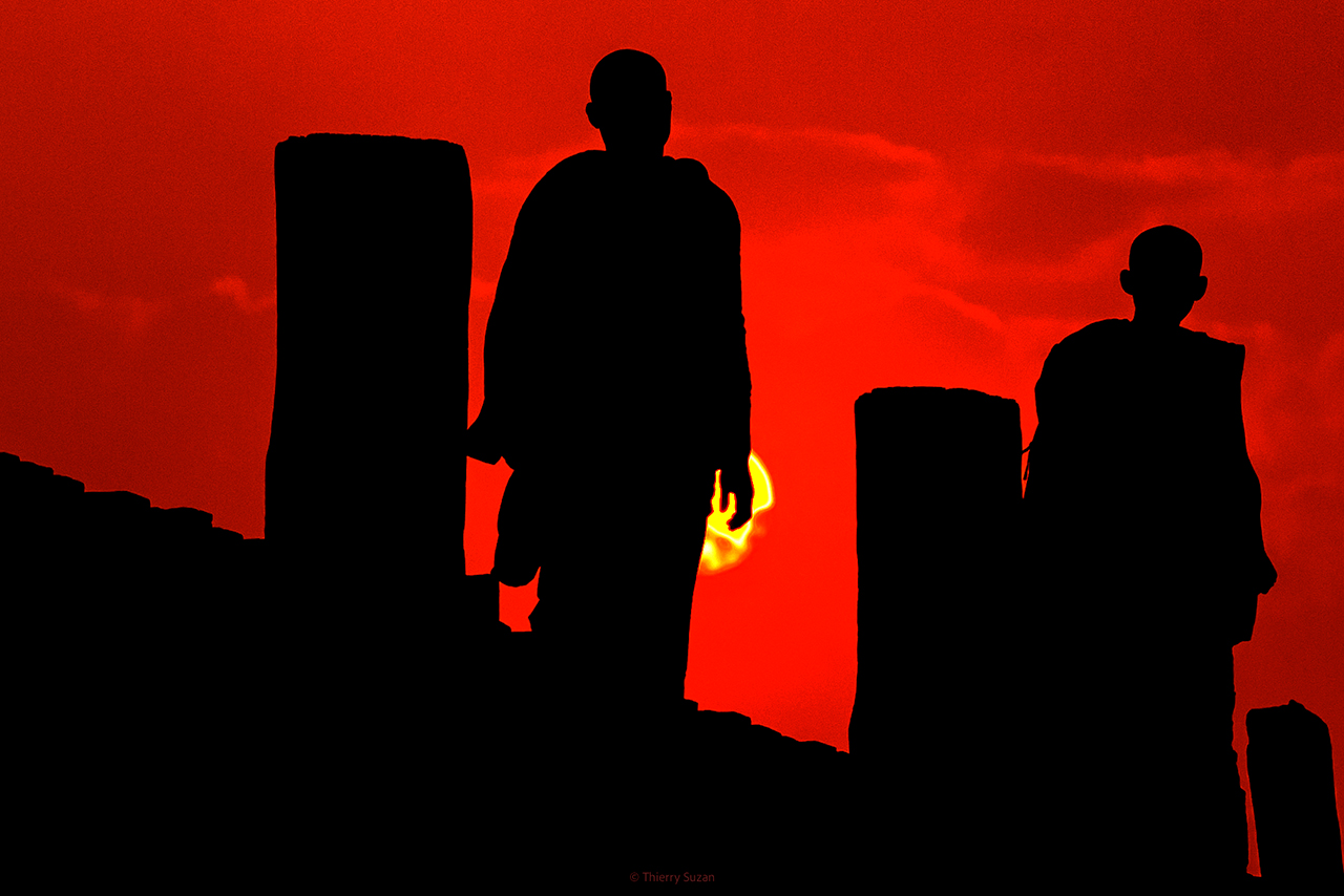 Buddhist monks walking on U Bein Bridge in Amarapura, Myanmar, at sunset
