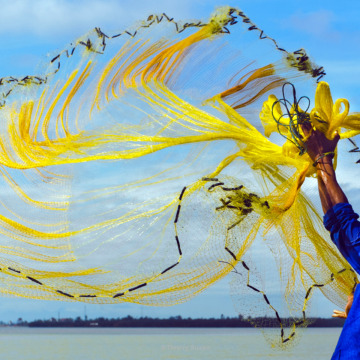 Fisherman casting his net from a boat on the Perfume River, Huế, Vietnam