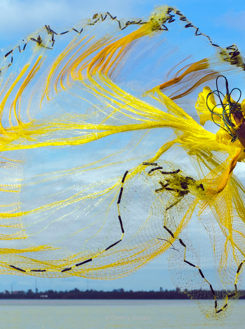 Fisherman casting his net from a boat on the Perfume River, Huế, Vietnam