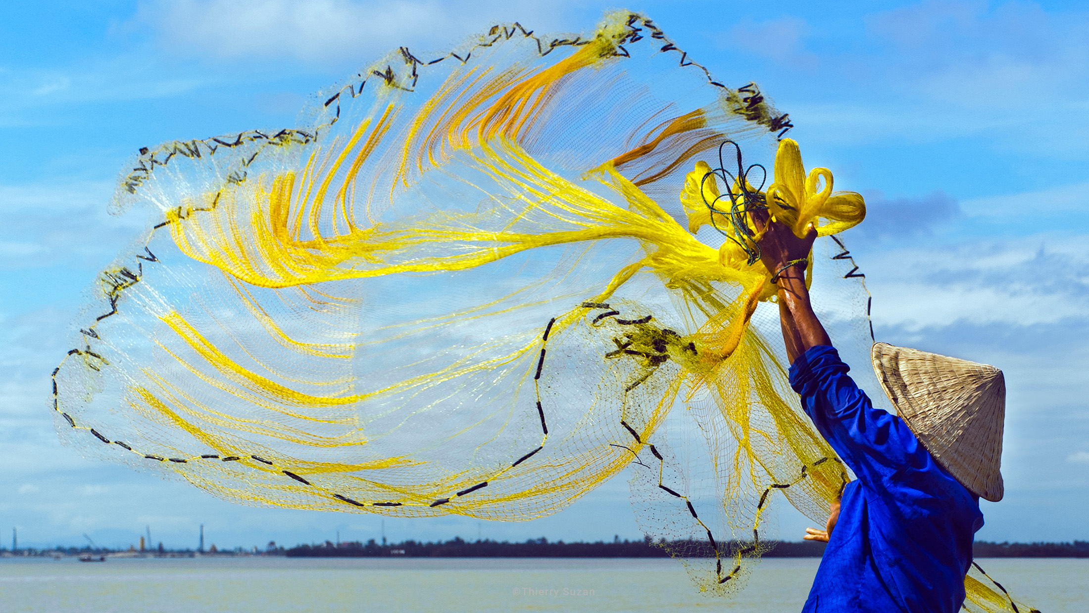Fisherman casting his net from a boat on the Perfume River, Huế, Vietnam