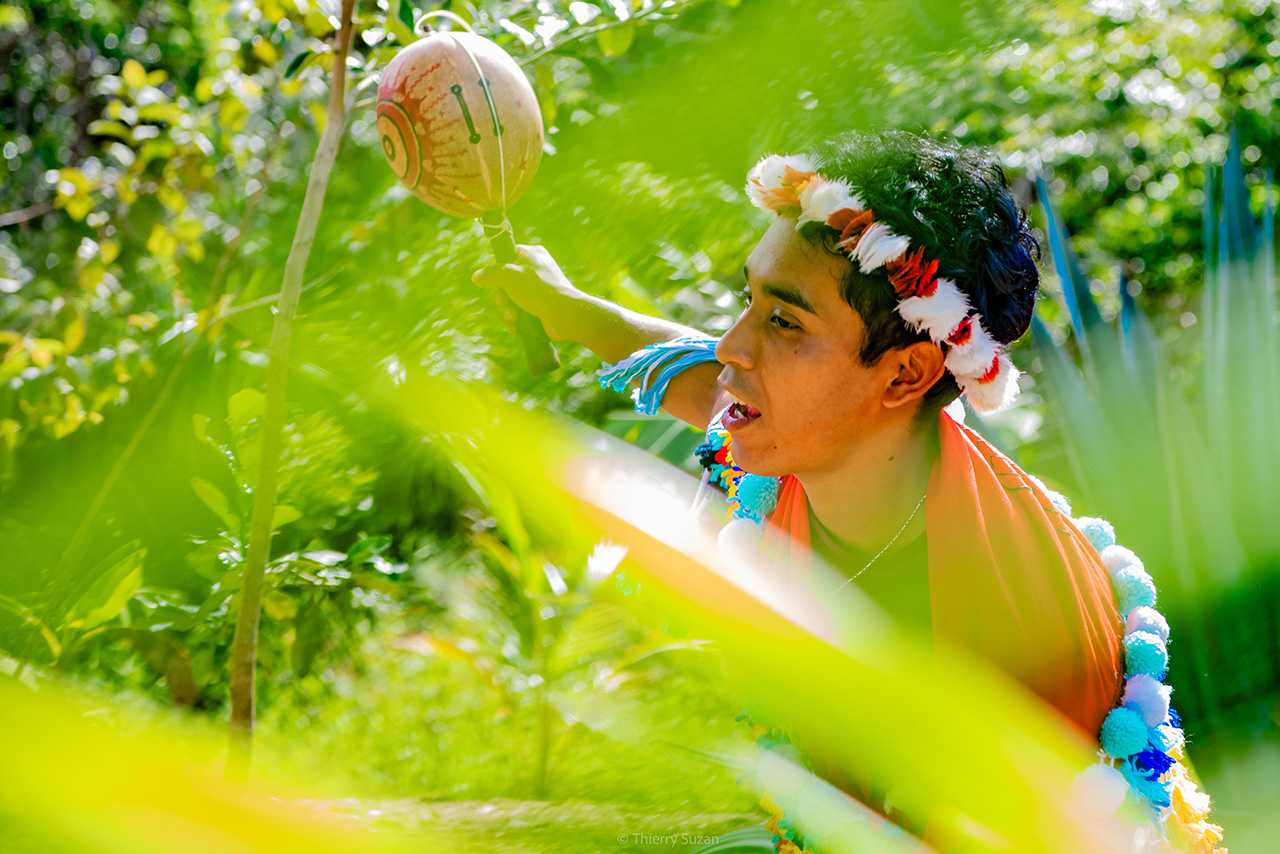 Portrait of a member of the Wayana Indigenous community in Amazonian French Guiana, wearing traditional dress and holding ceremonial maracas